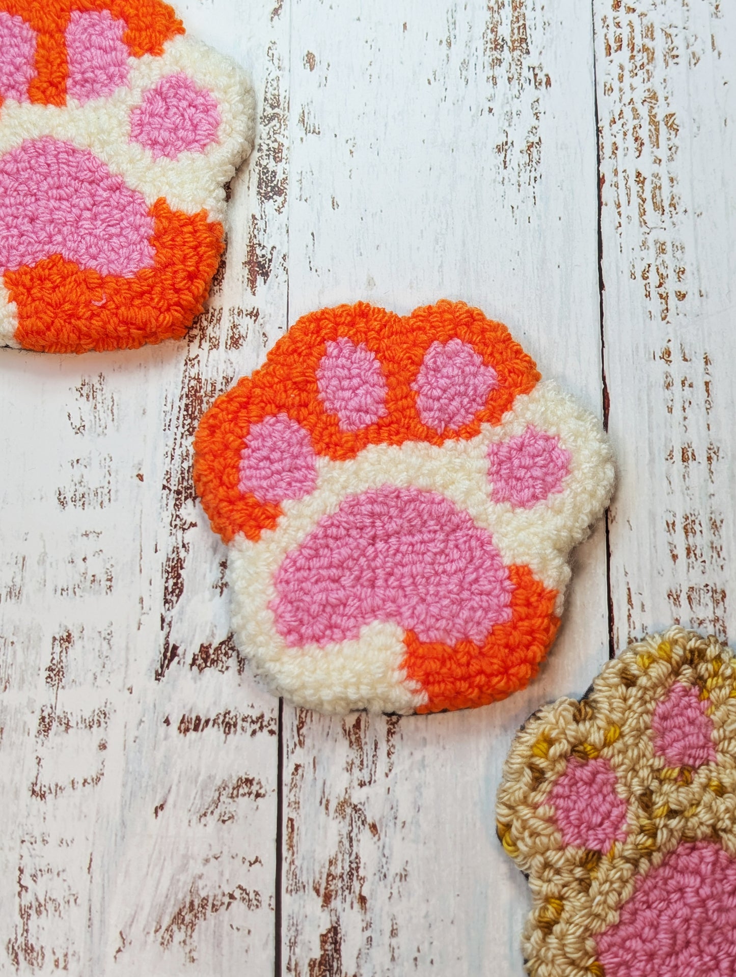 punch needle paw print mug rugs on a wood surface