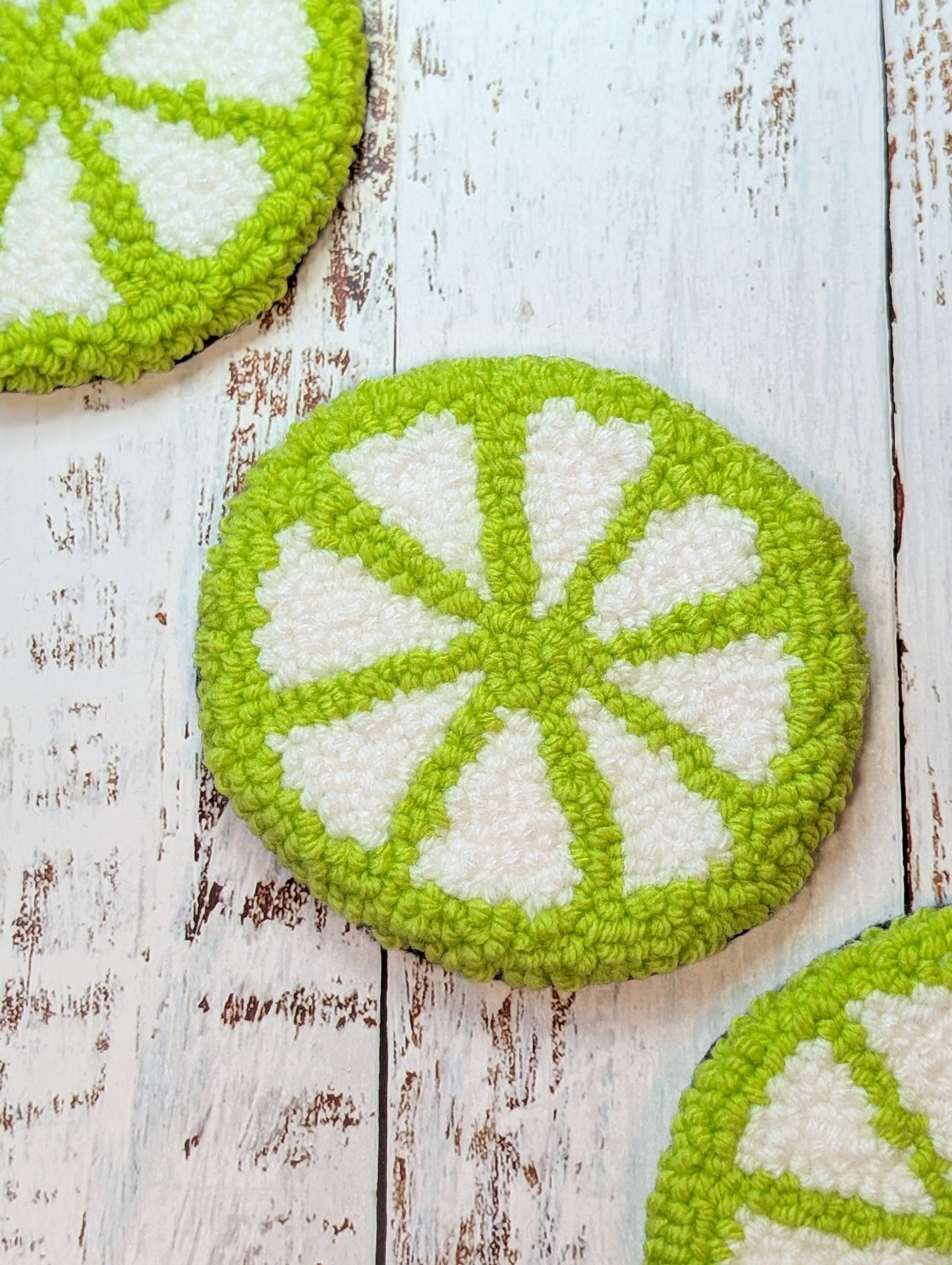 lime slice punch needle mug rug on a wood surface