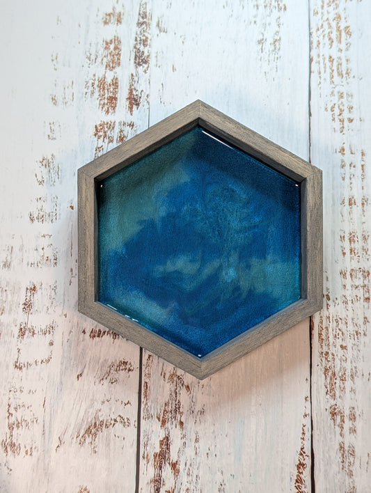 Hexagonal blue artwork in a wooden frame on a rustic wooden wall.