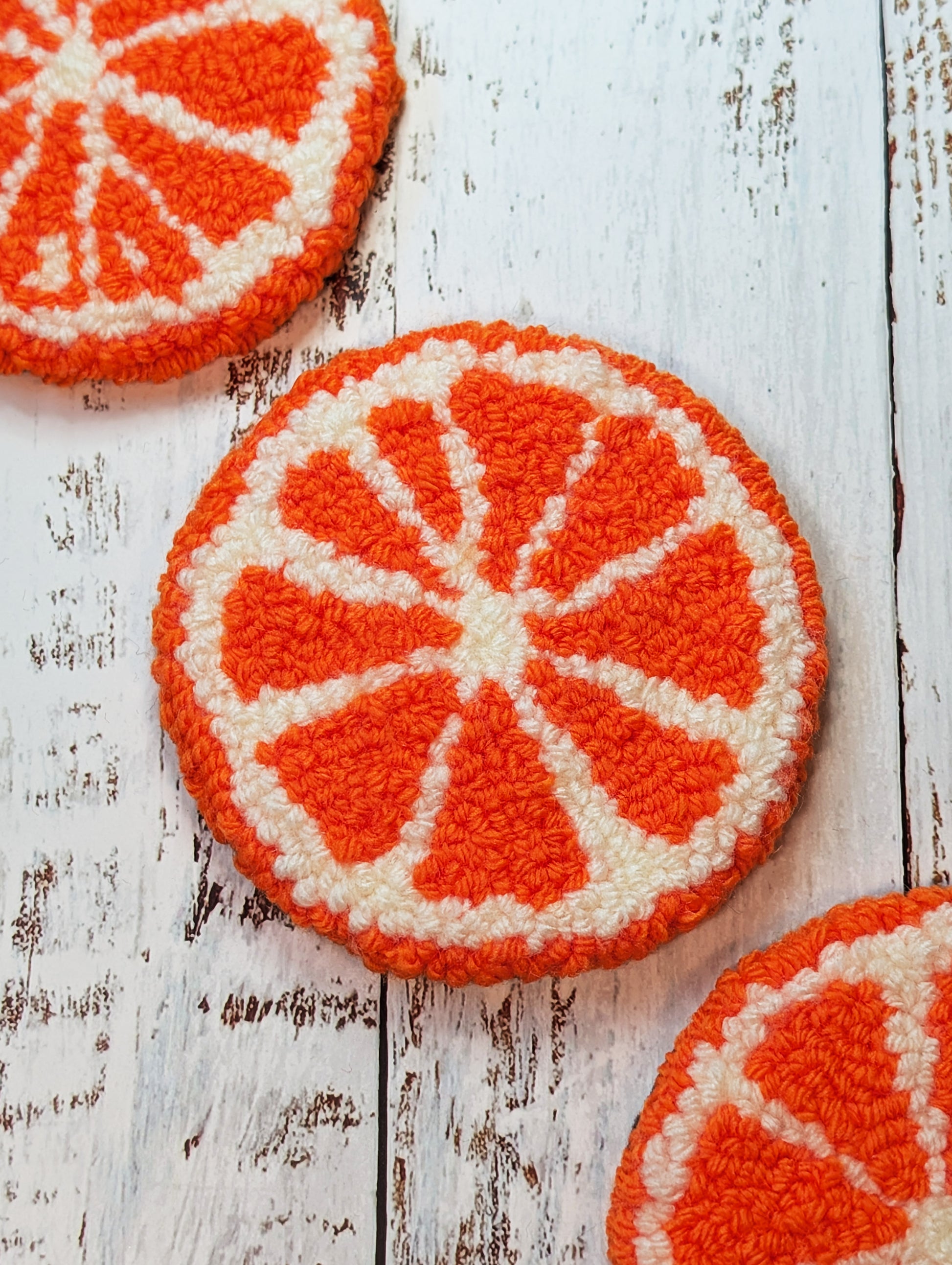 punch needle orange slice mug rug on wood surface